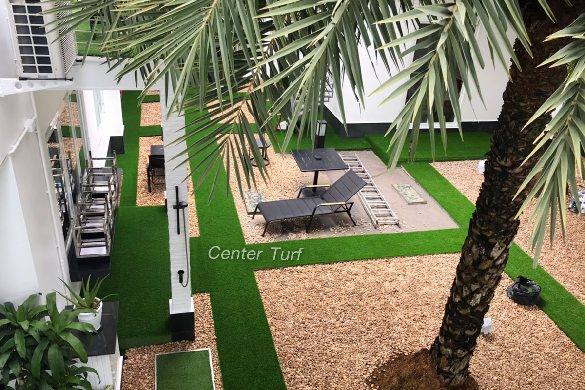 ตกแต่งทางเดินด้วยหญ้าเทียม สลับสวนหินสีน้ำตาลอ่อน เข้ากันได้ดีและลงตัว