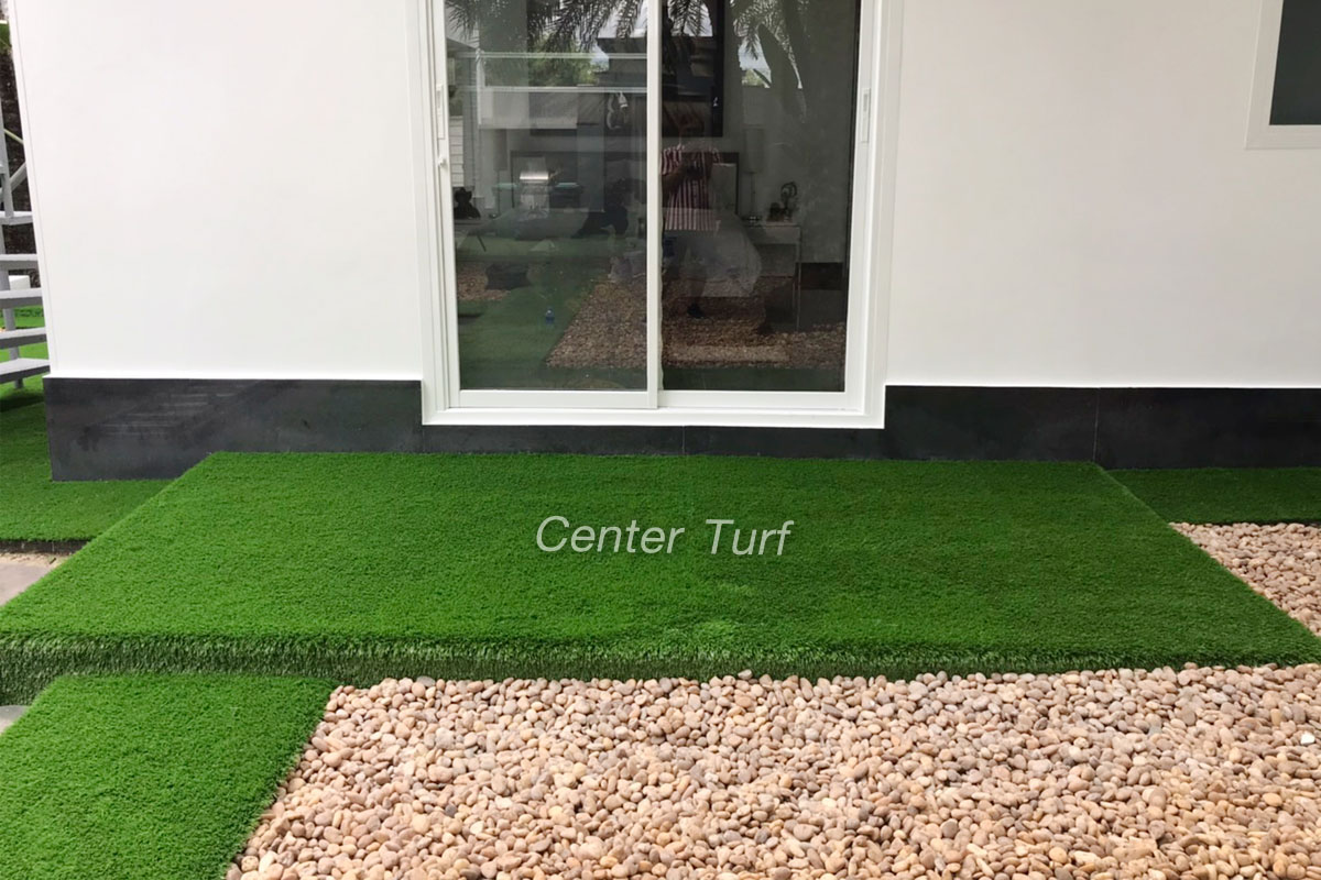 ตกแต่งทางเดินด้วยหญ้าเทียม สลับสวนหินสีน้ำตาลอ่อน เข้ากันได้ดีและลงตัว